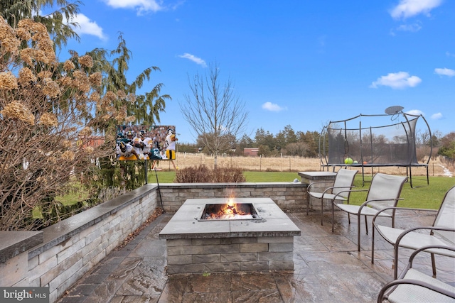 view of patio with a trampoline and a fire pit