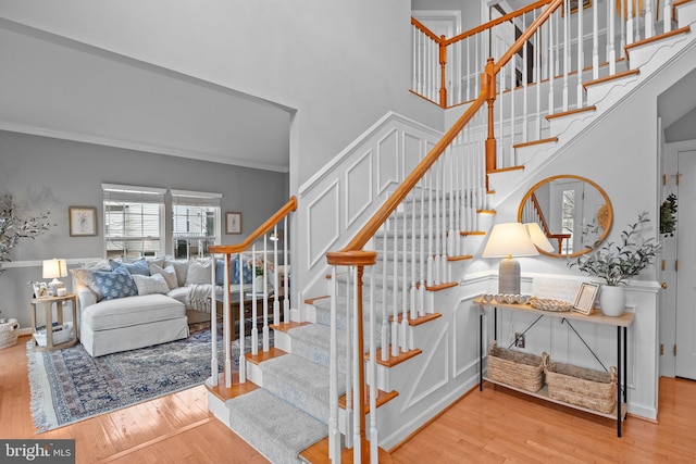 stairs with crown molding, a towering ceiling, and wood-type flooring