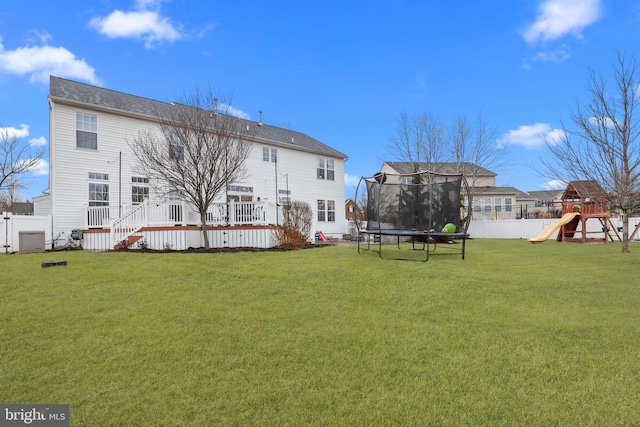 back of property featuring a playground, a wooden deck, a yard, and a trampoline