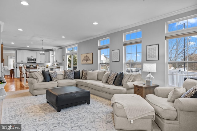 living room featuring crown molding, a wealth of natural light, and light wood-type flooring