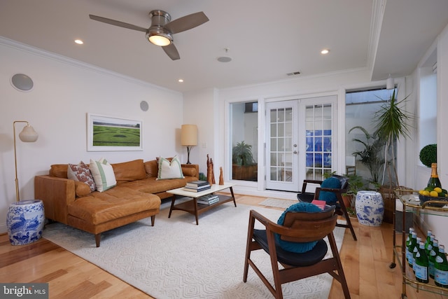 living room with crown molding, light hardwood / wood-style flooring, ceiling fan, and french doors