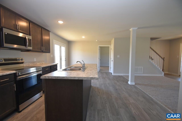 kitchen featuring sink, dark hardwood / wood-style flooring, dark brown cabinetry, stainless steel appliances, and a center island with sink