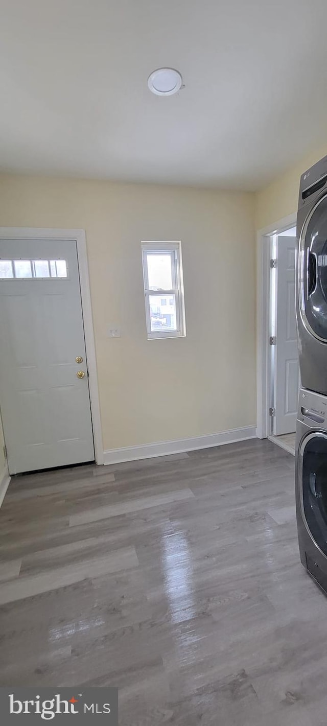 washroom with light hardwood / wood-style floors and stacked washing maching and dryer