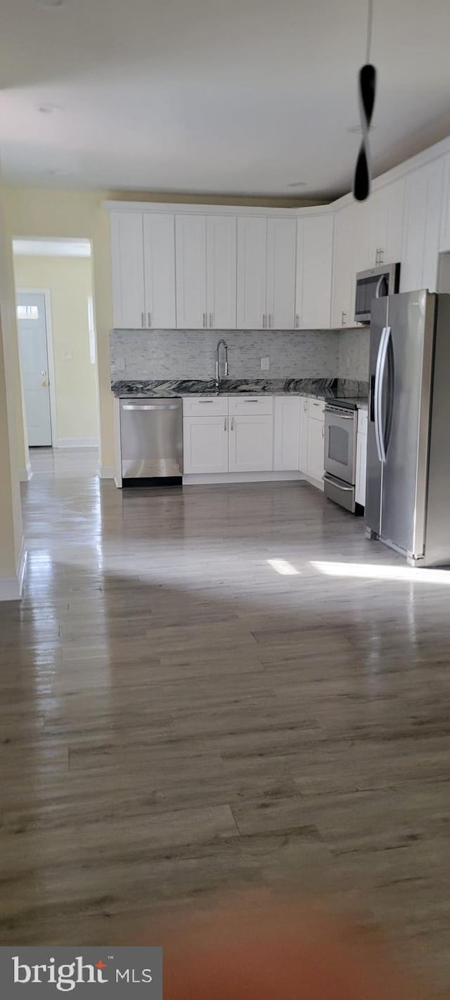 kitchen with sink, dark wood-type flooring, white cabinetry, stainless steel appliances, and decorative backsplash