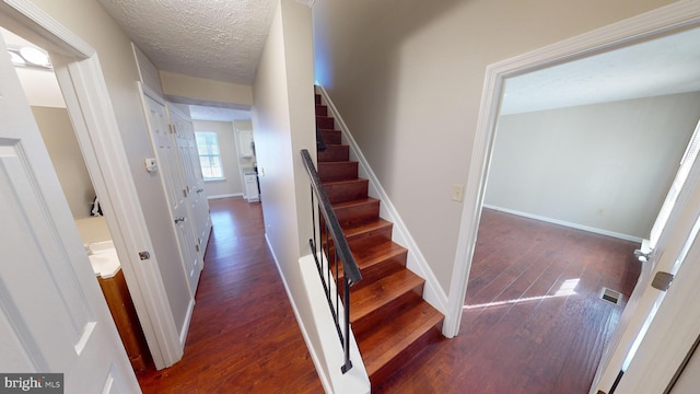 stairs featuring wood-type flooring and a textured ceiling