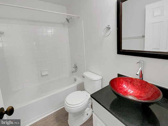 full bathroom featuring vanity, hardwood / wood-style floors, tiled shower / bath combo, and toilet