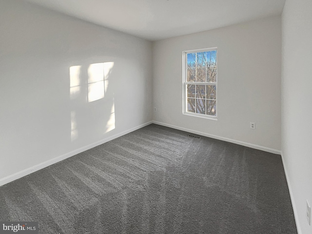 spare room featuring dark carpet