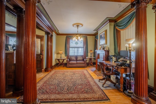 living area with a notable chandelier, ornamental molding, light hardwood / wood-style flooring, and ornate columns