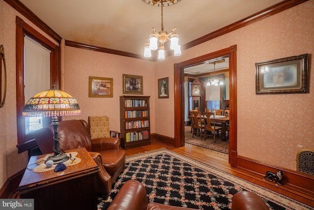 living area featuring wood-type flooring, ornamental molding, and an inviting chandelier