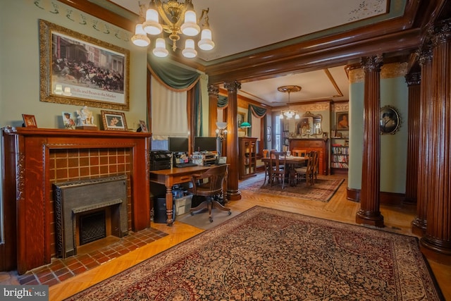 office area with parquet flooring, decorative columns, a tiled fireplace, ornamental molding, and an inviting chandelier