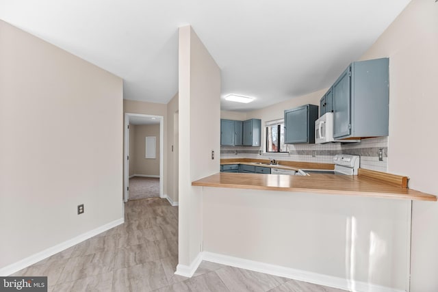 kitchen with blue cabinets, decorative backsplash, white appliances, and kitchen peninsula