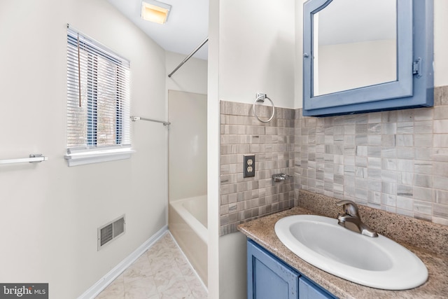 bathroom with vanity, backsplash, and a healthy amount of sunlight