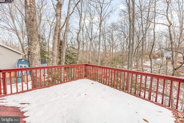 snow covered deck with a shed