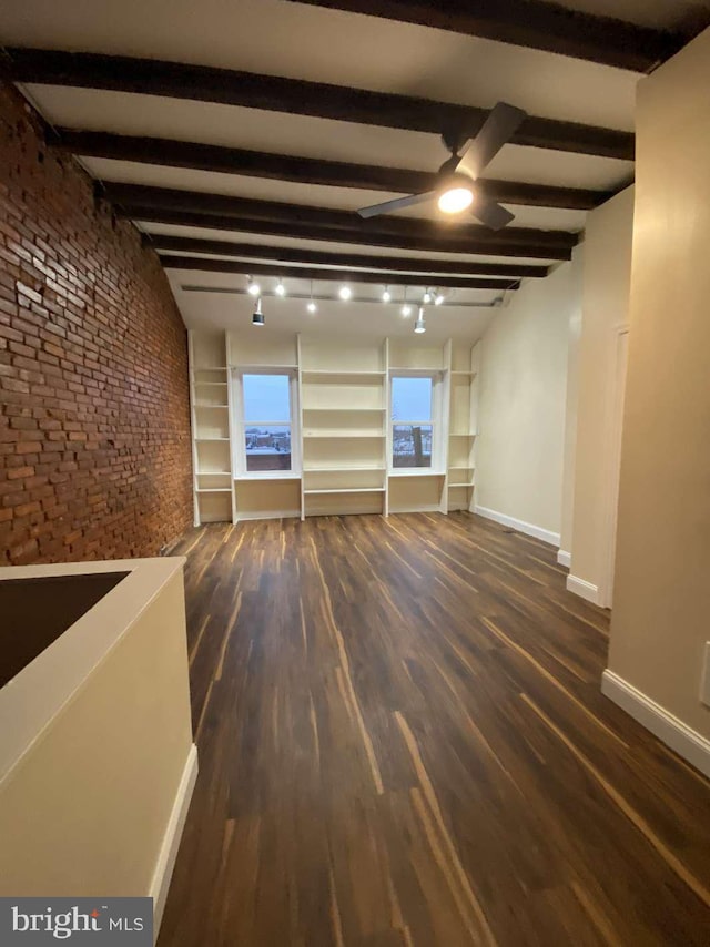 empty room featuring dark hardwood / wood-style floors, brick wall, and beam ceiling