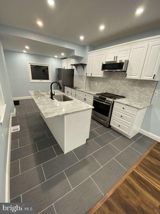 kitchen featuring extractor fan, appliances with stainless steel finishes, sink, white cabinets, and a kitchen island with sink