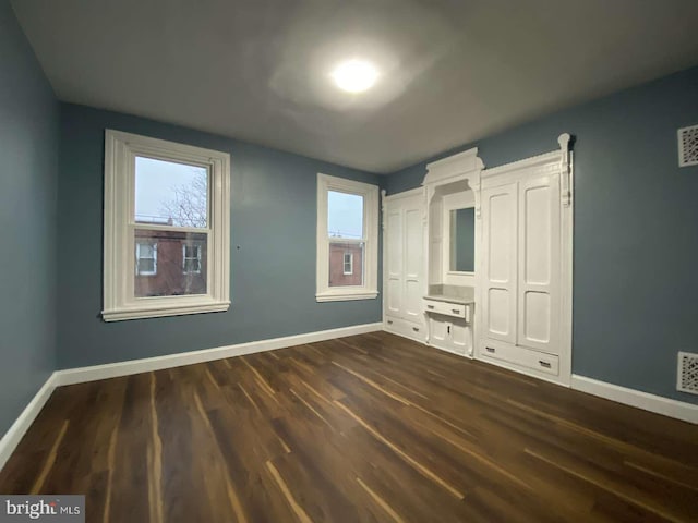 unfurnished bedroom featuring multiple windows and dark hardwood / wood-style flooring