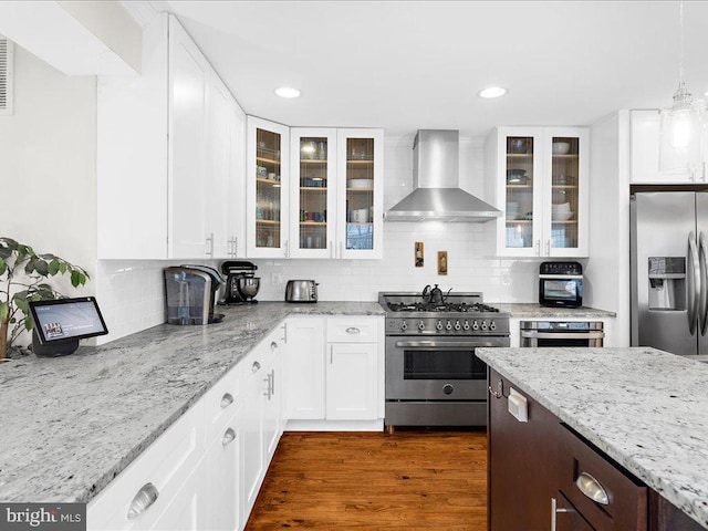 kitchen with stainless steel appliances, white cabinets, and wall chimney exhaust hood