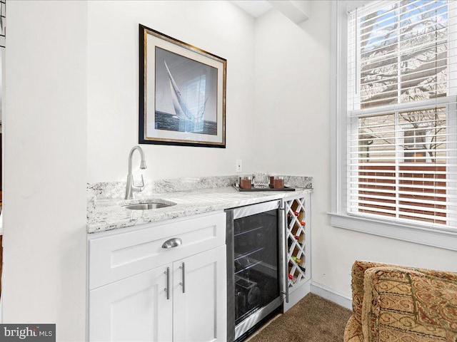 bar with white cabinetry, a healthy amount of sunlight, beverage cooler, and sink