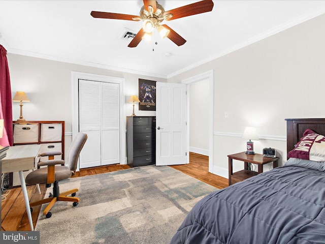 bedroom with wood-type flooring, ornamental molding, a closet, and ceiling fan