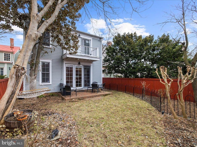 rear view of house featuring a yard and a balcony