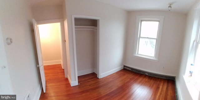 unfurnished bedroom featuring multiple windows, wood-type flooring, and a closet