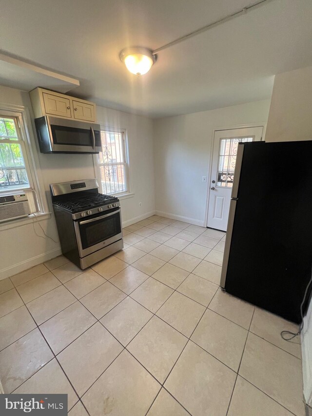 kitchen featuring light tile patterned flooring, stainless steel appliances, cooling unit, and light brown cabinets