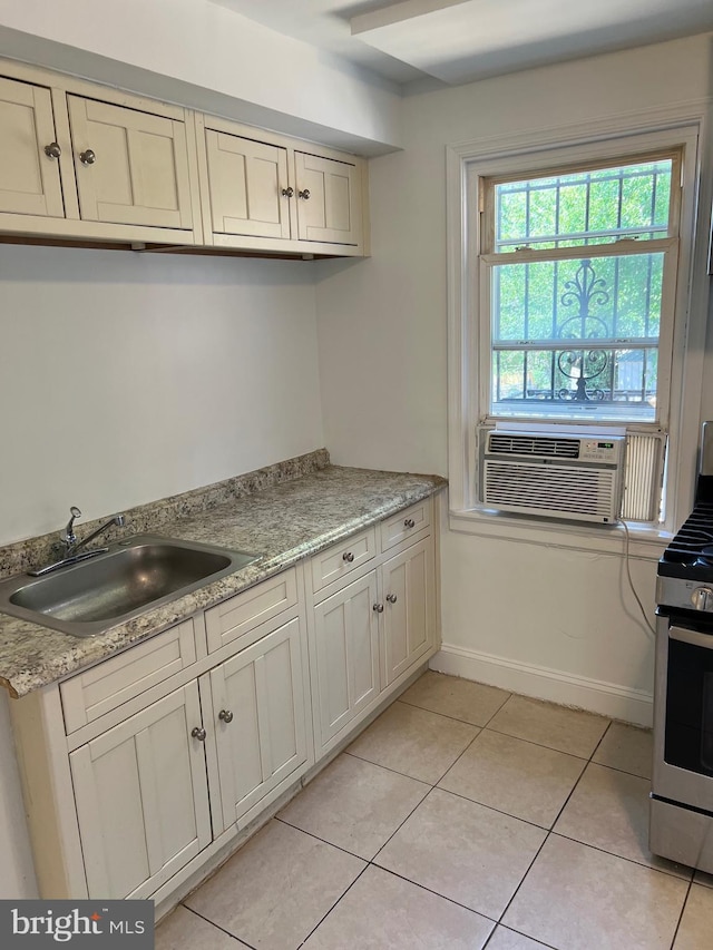 kitchen with sink, light tile patterned floors, stainless steel gas range, cooling unit, and light stone counters