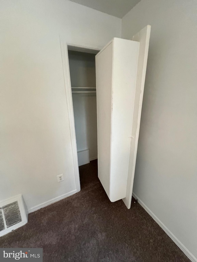 unfurnished bedroom with a closet and dark colored carpet