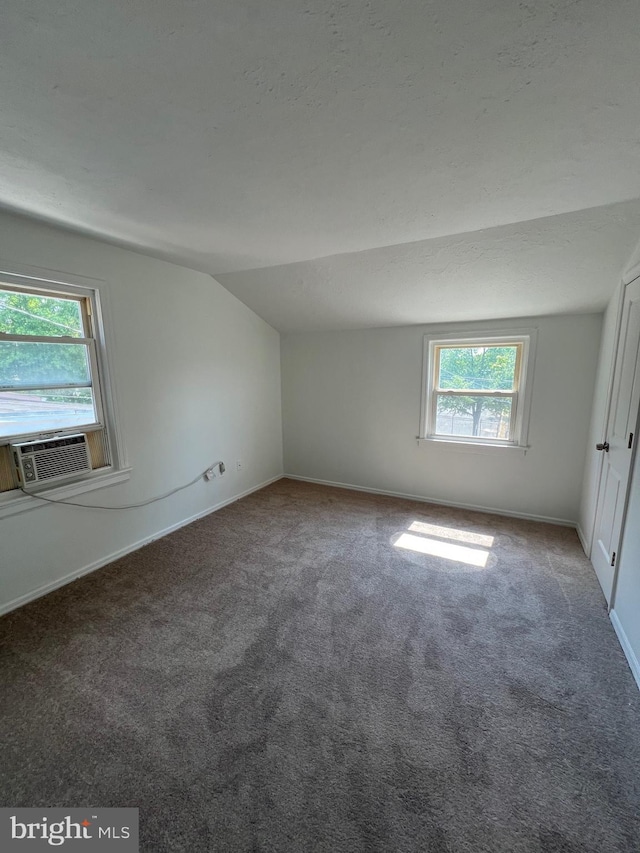 spare room featuring vaulted ceiling, carpet, and cooling unit