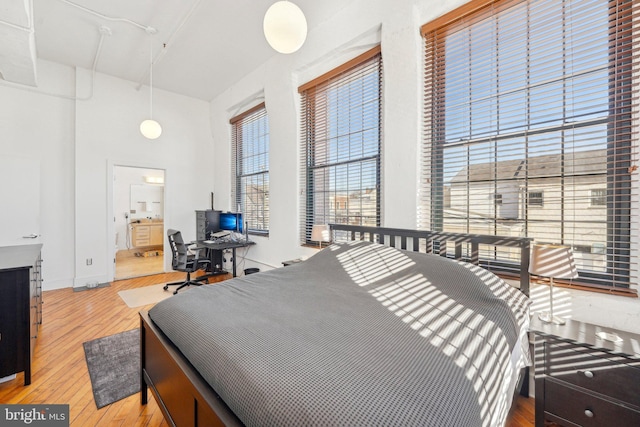 bedroom with light wood-type flooring and ensuite bathroom