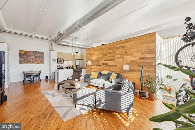 living room with a towering ceiling, wooden walls, and light wood-type flooring