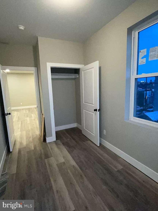 unfurnished bedroom with dark hardwood / wood-style flooring and a closet