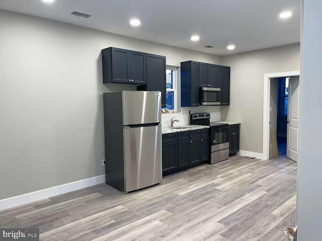 kitchen with stainless steel appliances, tasteful backsplash, sink, and light hardwood / wood-style floors