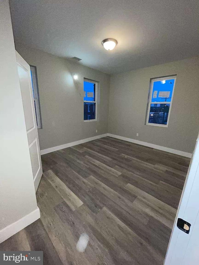 empty room featuring dark hardwood / wood-style flooring and a textured ceiling