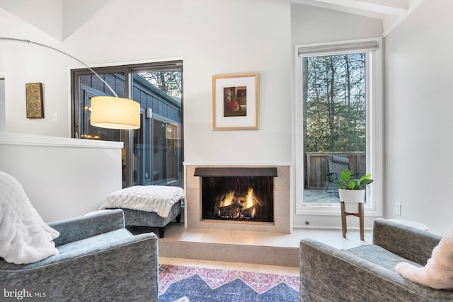 living area with a tile fireplace and lofted ceiling