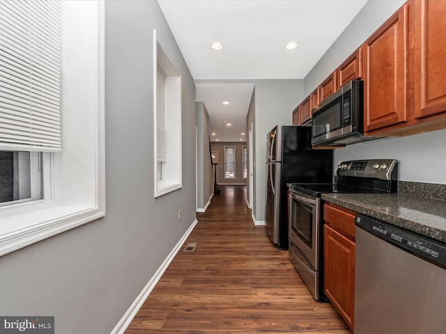 kitchen with dark wood-type flooring, stainless steel appliances, and dark stone countertops