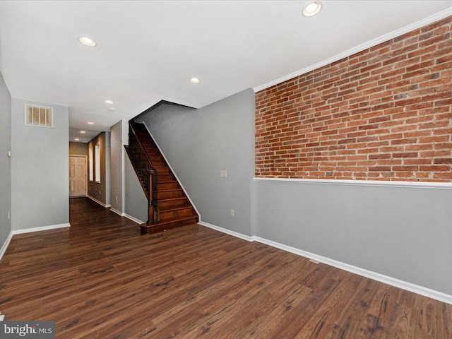 unfurnished room with brick wall and dark hardwood / wood-style floors