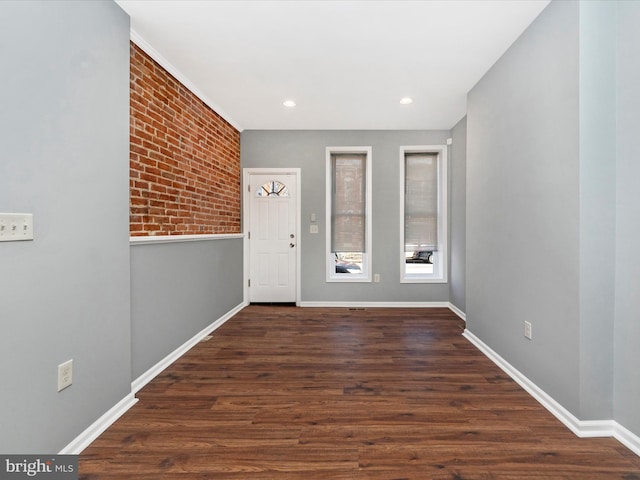 entryway with dark hardwood / wood-style floors and brick wall