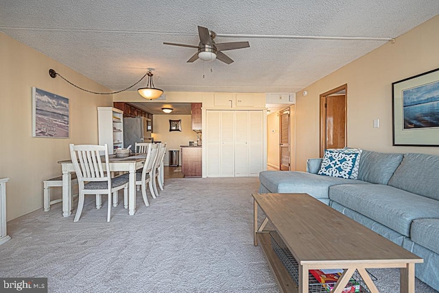 living room with ceiling fan, carpet, and a textured ceiling