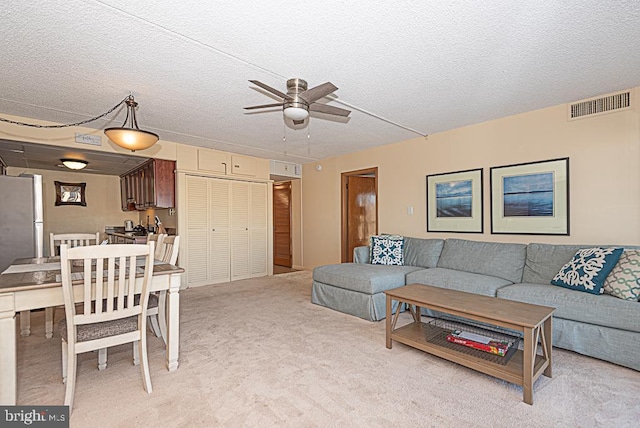 carpeted living room featuring ceiling fan and a textured ceiling