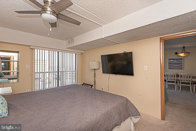 carpeted bedroom featuring a textured ceiling and ceiling fan