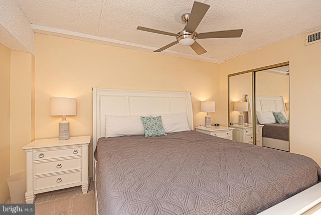 carpeted bedroom with ceiling fan, a textured ceiling, and a closet