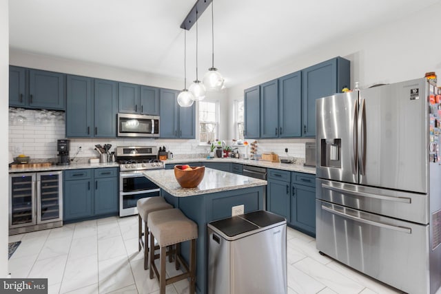 kitchen featuring blue cabinetry, stainless steel appliances, a kitchen island, wine cooler, and a kitchen breakfast bar