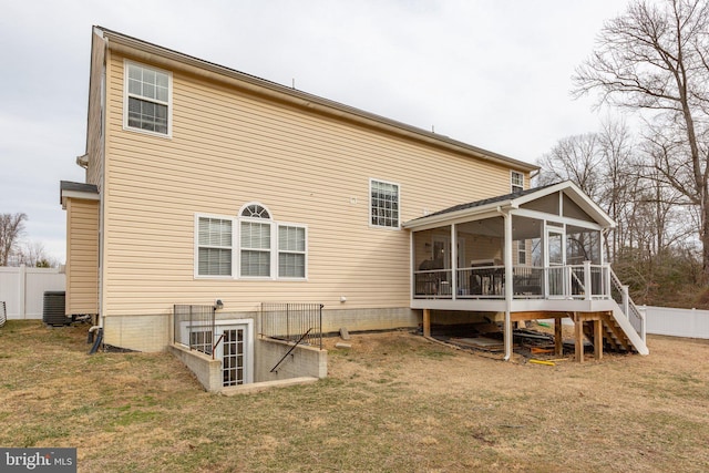 rear view of house featuring a yard and a sunroom