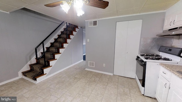 kitchen featuring white gas range, backsplash, white cabinets, and ceiling fan