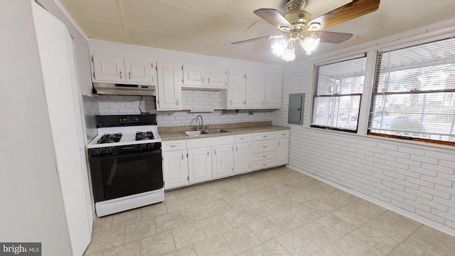 kitchen with sink, gas stove, electric panel, brick wall, and white cabinets