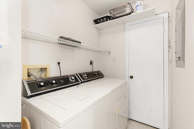 clothes washing area with independent washer and dryer, electric panel, and a textured ceiling