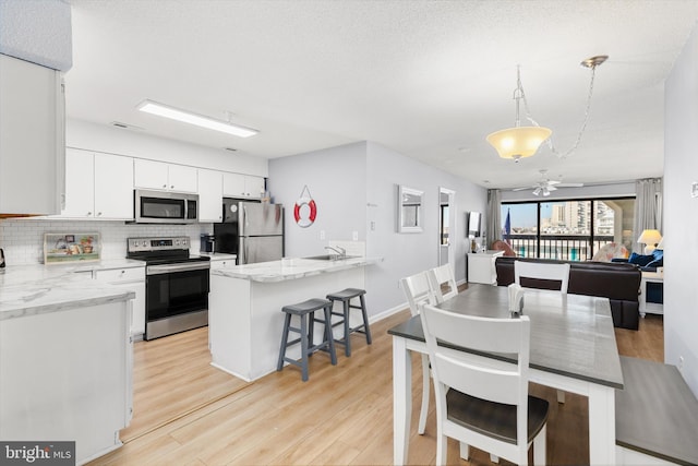 dining area featuring sink, light hardwood / wood-style flooring, and a textured ceiling