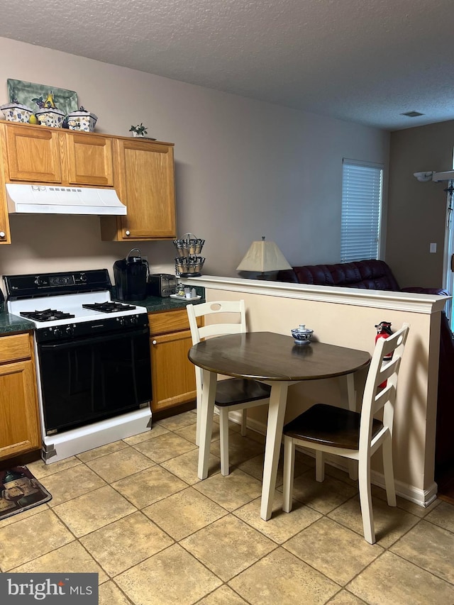 kitchen featuring light tile patterned floors, gas range, and a textured ceiling