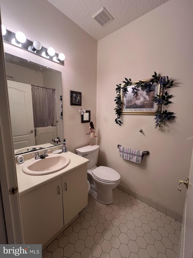 bathroom with vanity, a textured ceiling, tile patterned floors, toilet, and walk in shower